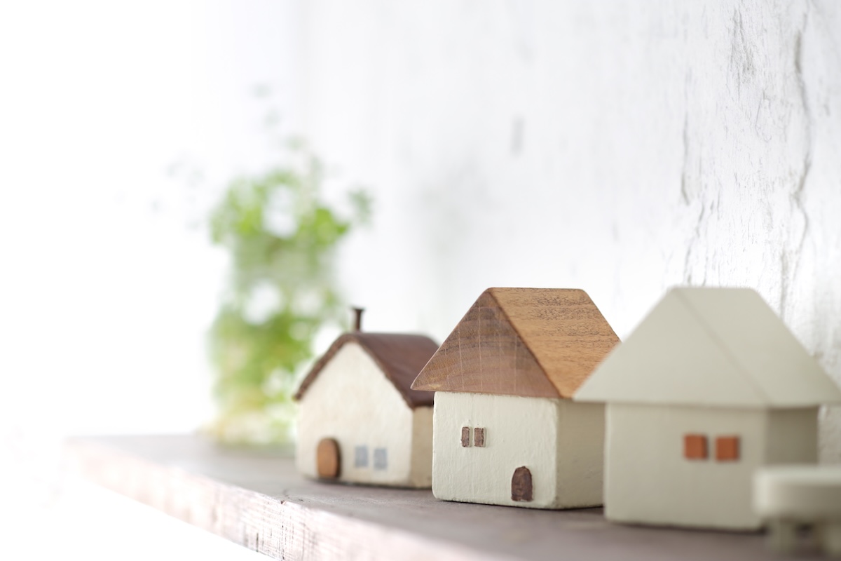 ナチュラルな木の棚に並ぶ小さな家の模型。自然と調和した暮らしやエコ住宅のイメージ。