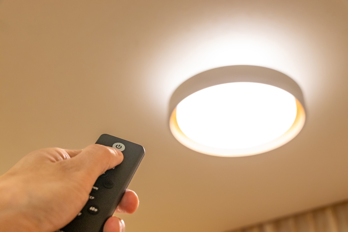 リモコンで照明を操作する手元。こまめなオン・オフが節電につながる。