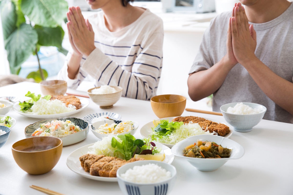 家庭の食卓を囲んで食事をする家族。食費や生活費をテーマにしたイメージ。
