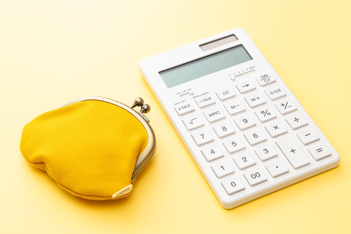黄色い財布と電卓。光熱費や電気代を見直す家計管理のイメージ。