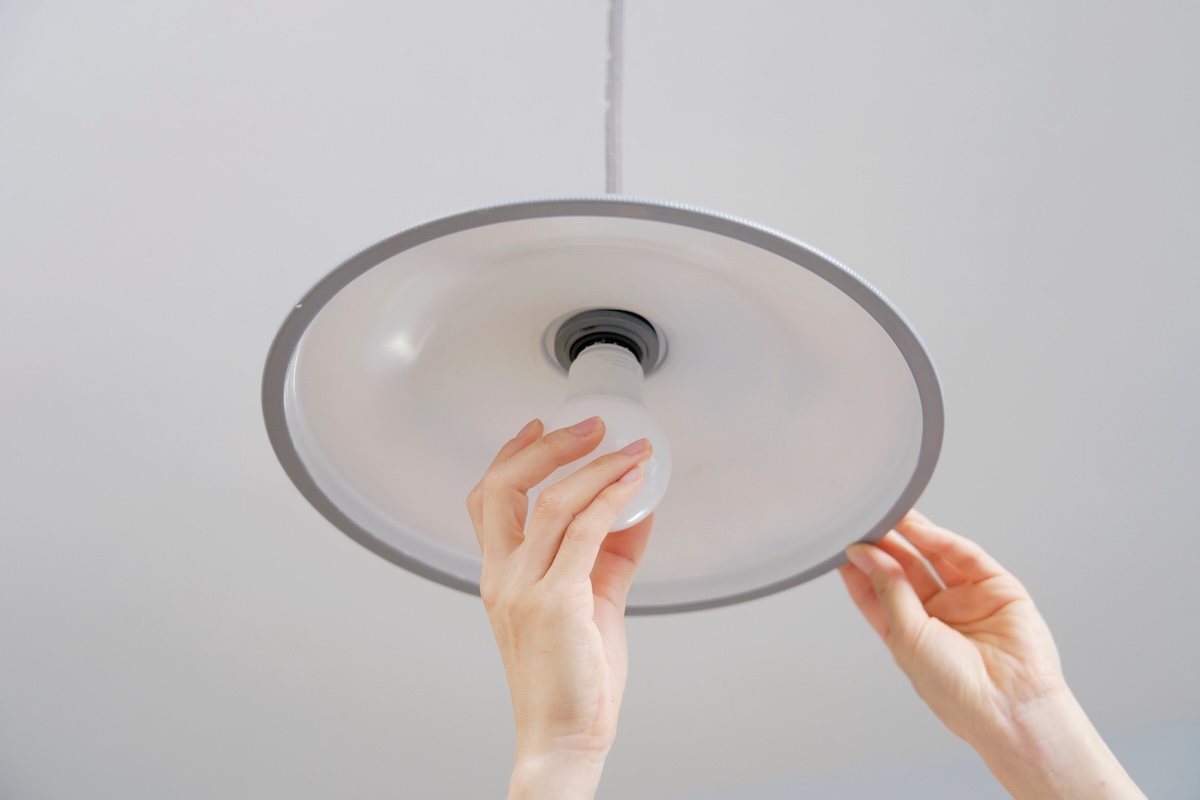 LED電球を取り付ける手元。省エネ照明への交換で電気代削減を意識したイメージ。
