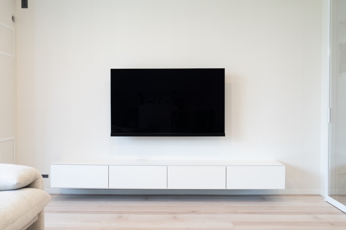 壁掛けテレビが設置されたリビング。家電の待機電力や節電対策を意識した暮らしのイメージ。