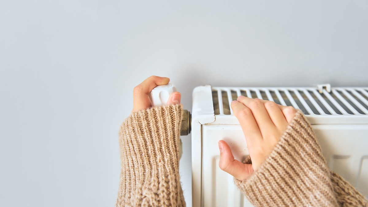 セントラルヒーティングの温度調整ノブを操作する手元。エネルギー効率の高い暖房管理をイメージした写真。