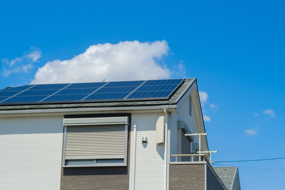 屋根に太陽光パネルが設置された一戸建て。オール電化住宅の光熱費を示すイメージ画像。