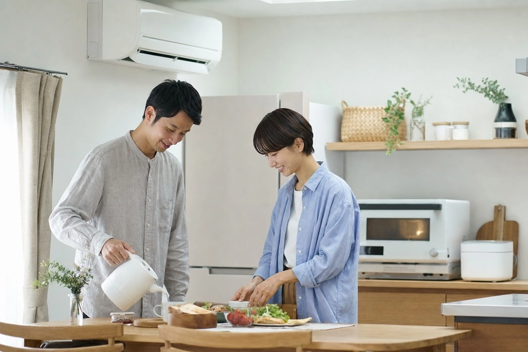 電子レンジやケトルなどの家電を使いながら朝食を準備する夫婦。適切な契約アンペアで快適に暮らすイメージ。